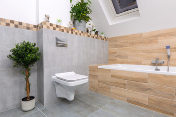 Modern bathroom interior with gray tiles and wooden decors © Patryk Kosmider
