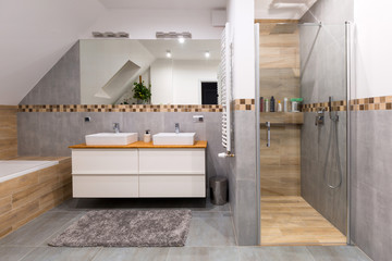 Modern bathroom interior with gray tiles and wooden decors