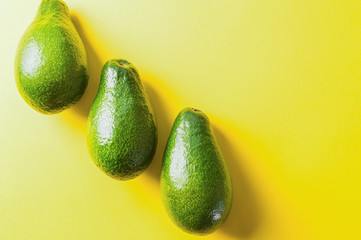 Green raw fresh avocado - source of vitamins and nutrition. On the yellow background