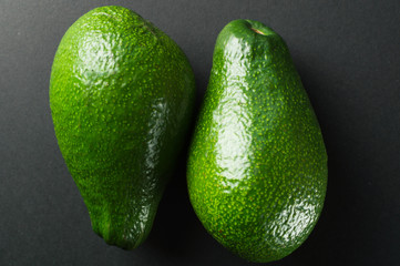 Organic fruit - raw frash avocado top view, on the black background.
