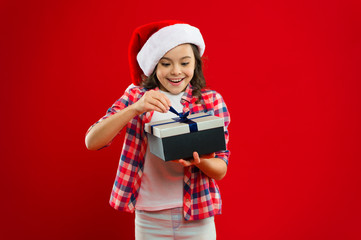 Festive decor. New year party. Santa claus kid. Little girl child in santa red hat. Present for Xmas. Childhood. Happy winter holidays. Small girl. Christmas shopping. Little secret