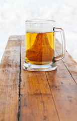 Glass mug with fresh cold beer on wooden bench