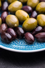 Green and dark olives on a blue greek plate.