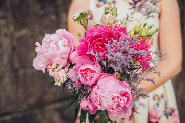 Close up image of beautiful peonies bouquet holding by young girl