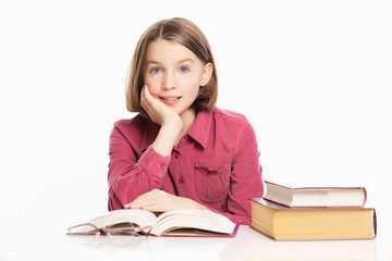 Beautiful teen girl sitting at a table with books, white background