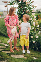 Fototapeta premium Summer portrait of two stylish kids posing in flower garden on a nice sunny day