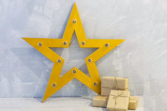 Gift box wrapped in craft paper with gold ribbon and stars on gray stone