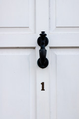 The house number 1 on a white painted door in Hertfordshire.