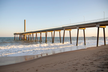 pier on the beach with waves and blue sky (costa azul, rio das ostras, rio de janeiro, brazil)