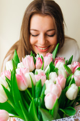 Close up of young woman closes her eyes and smiles at large pink tulips flowers bouquet. natural beauty. spring bride bouquet. happy women's day.