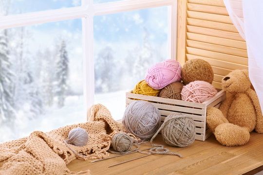 Woolen yarn and fabric on the window sill. Beautiful view outside the window - winter scenery and snow.