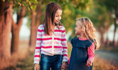 Two little girls walks together in the park. Childhood, nature, lifestyle