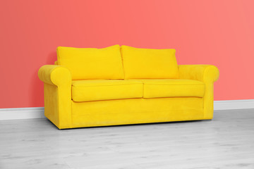 Room interior with comfortable sofa near color wall