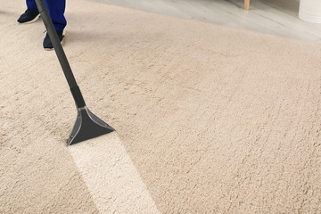 Man removing dirt from carpet with professional vacuum cleaner in room