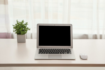 Fototapeta premium Laptop with computer mouse on table indoors. Space for text