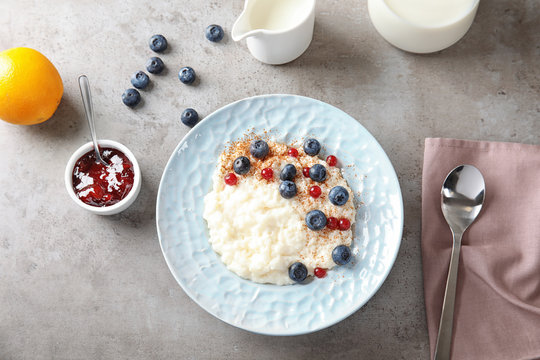Creamy rice pudding with red currant and blueberries in bowl served on grey table, top view