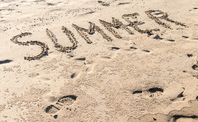 summer written in the sand of the beach