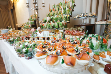 Beautifully decorated catering banquet table with profiteroles, salads and cold snacks. Variety of tasty delicious snacks on the table. Wedding table serving. Meat and vegetables