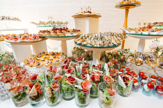 Beautifully decorated catering banquet table with profiteroles, salads and cold snacks. Variety of tasty delicious snacks on the table. Wedding table serving. Meat and vegetables