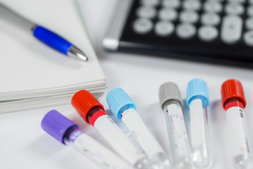 Medicine bottles for samples next to calculator and notebook in hospital or laboratory, closeup on white background