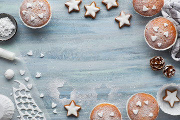 Top view of the table with sugar-sprinkled muffins, fondant icing and Christmas star cookies on blue wood