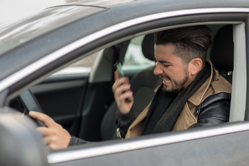 Fototapeta na wymiar Handsome young man fighting on the phone while driving his car