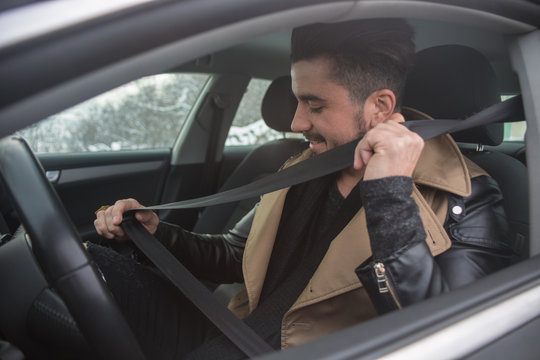 Handsome Young Man Putting On Seatbelt In A Car