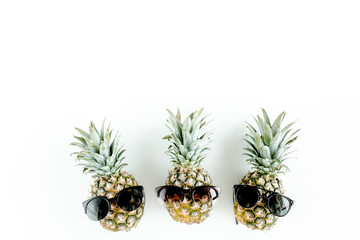 Hipster pineapples in sunglasses on white background. Flat lay, top view
