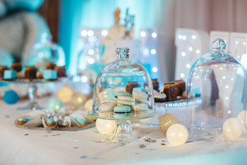 Delicious wedding reception candy bar dessert table full with cakes, sweets, macaroons, eclairs and other types of bakery