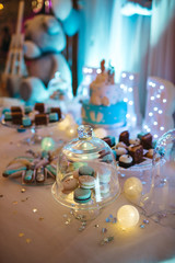 Delicious wedding reception candy bar dessert table full with cakes, sweets, macaroons, eclairs and other types of bakery