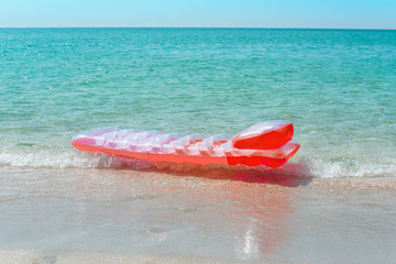 Beautiful pink air mattress lies in the blue sea water.