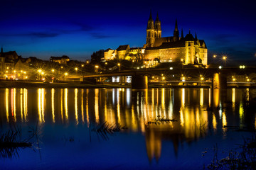 Fototapeta na wymiar Panoramic night view over river Elbe at the Albrechtsburg in Meißen Germany with bright light reflections.