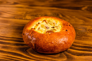 Sweet bun with cottage cheese and raisins on wooden table