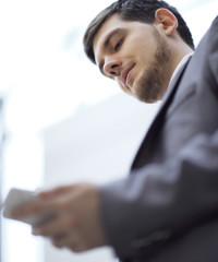 close up.serious businessman reading text message on smartphone