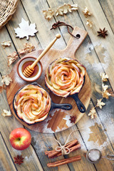 Homemade puff pastry with rose shaped apple slices baked in iron skillets on wood