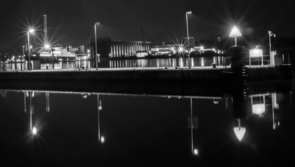 Black and white night scene of a pier in front of docks in Flensburg Germany.