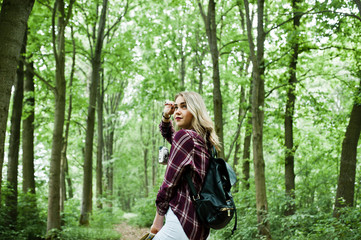 Fototapeta na wymiar Portrait of a young beautiful blond woman in tartan shirt holding a map in the forest.