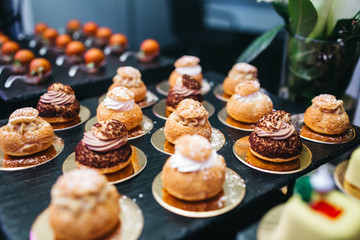 Beautifully decorated catering banquet table with profiteroles, salads and cold snacks. Variety of tasty delicious snacks on the table. Wedding table serving. Meat and vegetables