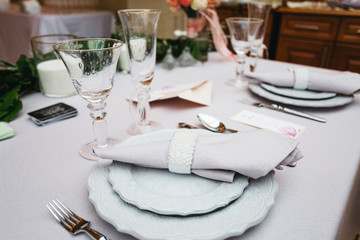 Wedding presidium in restaurant, free space. Wedding banquet table for newlyweds with flowers, greenery, pink cloth and bulbs. Lush floral arrangement on wedding table. Luxury wedding decorations