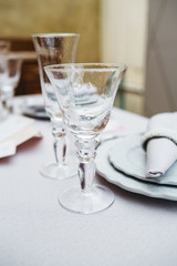 Dinner table serving. Violet and beige tones, pastel colors. Beautiful decoration of wedding banquet in restaurant with glasses, plates, forks and knives, white tablecloth.