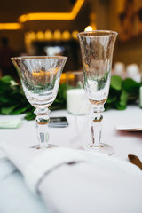 Dinner table serving. Violet and beige tones, pastel colors. Beautiful decoration of wedding banquet in restaurant with glasses, plates, forks and knives, white tablecloth.