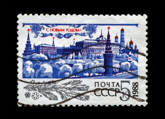 Kremlin with red star, trees under snow for Chistmas, circa 1987. Happy New Year 1988 as text. canceled vintage post stamp printed in the USSR isolated on black background.