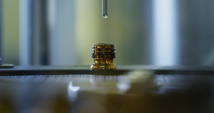 Close up of production of medicines in glassware bottles on automatic lines in a pharmaceutical factory. 