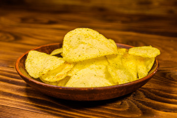 Ceramic plate with potato chips on wooden table