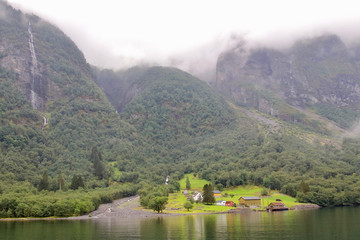 Obraz premium Main view of Styvi village and its farm museum with surrounding waterfalls on background. This tinny village is located on the western shore of the Nærøyfjord, north of Gudvangen village, Norway.