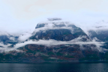 Fog and mountains landscape all along te shores of the Naeroyfjord, north of Gudvangen village, Norway.