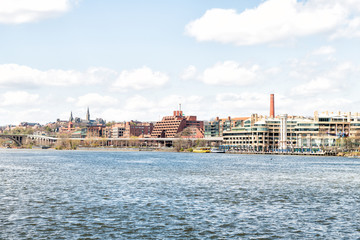 Fototapeta na wymiar Cityscape, skyline view of Potomac river, Georgetown waterfront park in Washington, DC, District of Columbia, water waves on sunny spring day, Whitehurst freeway, blue sky ,clouds