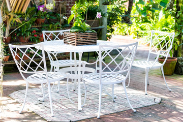 White cast iron chairs, table in outdoor, outside sitting area, garden, patio, porch, many potted...