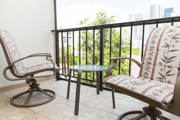 Chairs, armchairs, small table in balcony of apartment, house, home in Miami, Florida with view on skyscrapers, buildings, railing