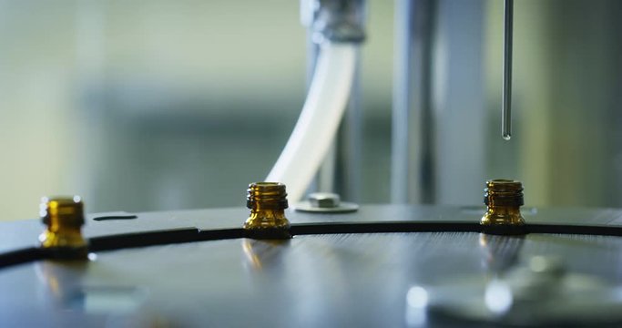 Close up of production of medicines in glassware bottles on automatic lines in a pharmaceutical factory. 